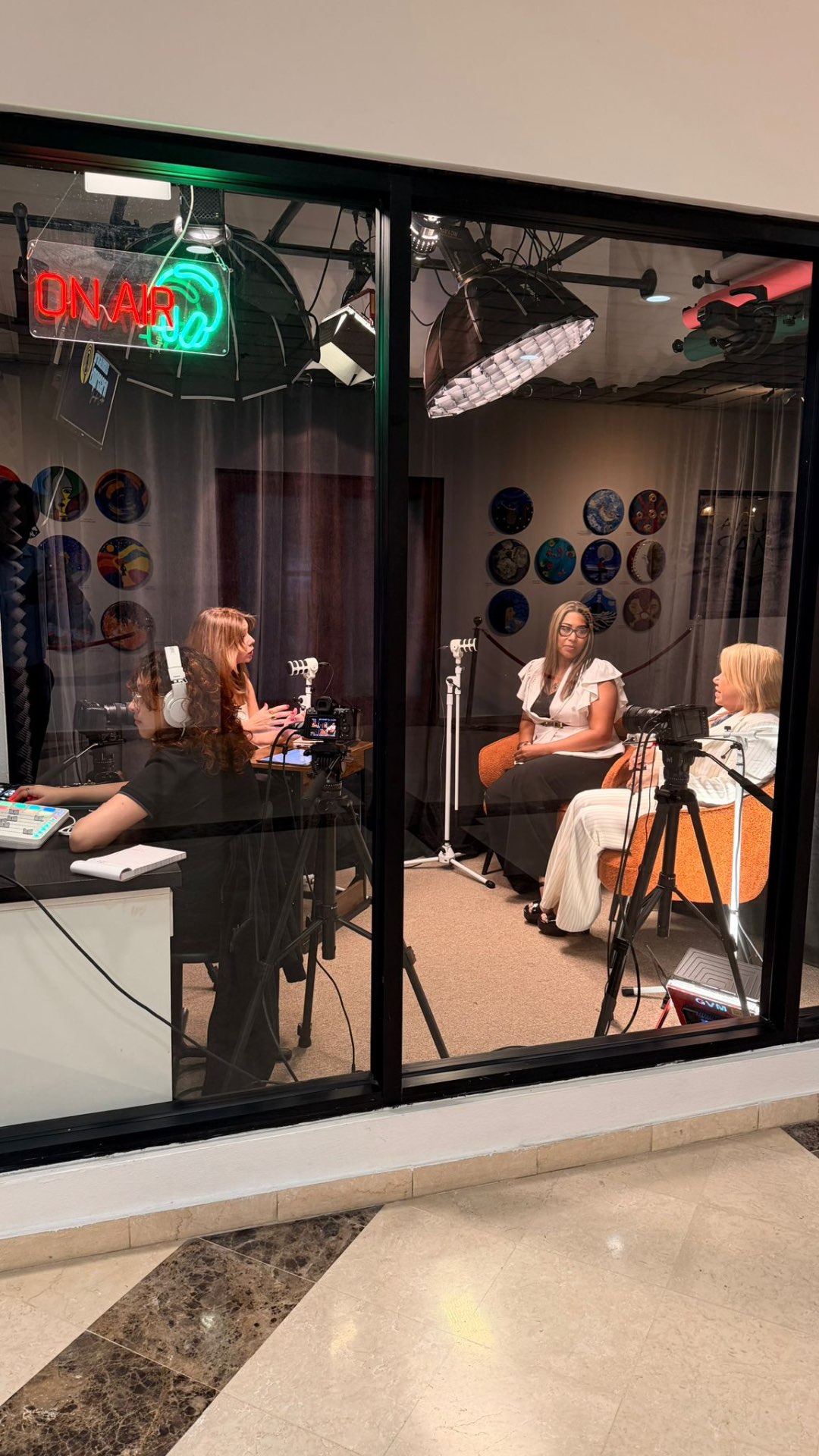 Estudio de Link Studios visto desde el cristal con letrero de neón ON AIR mientras se graba una entrevista